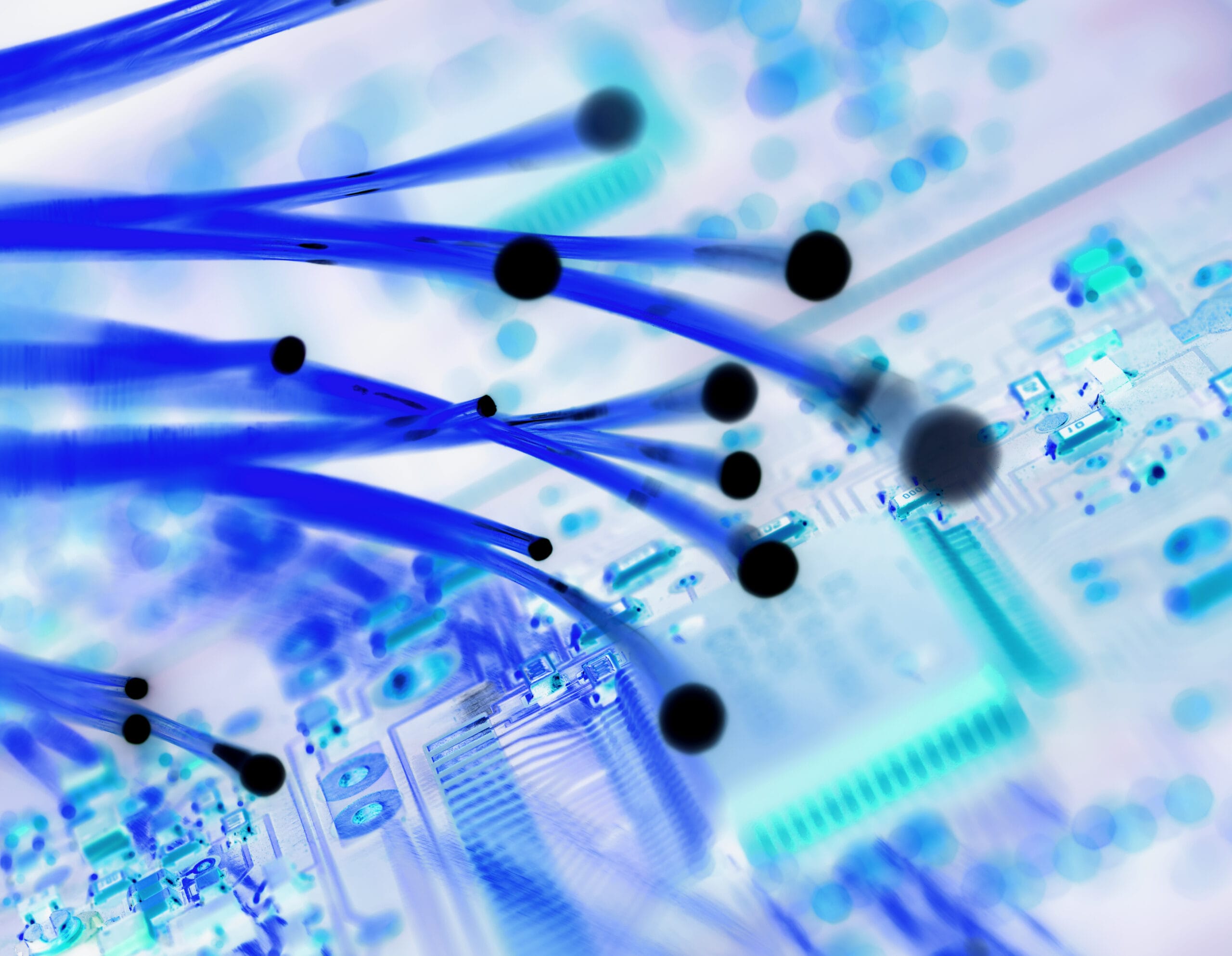 Close-up of a circuit board with blue fiber optic cables extending from it.