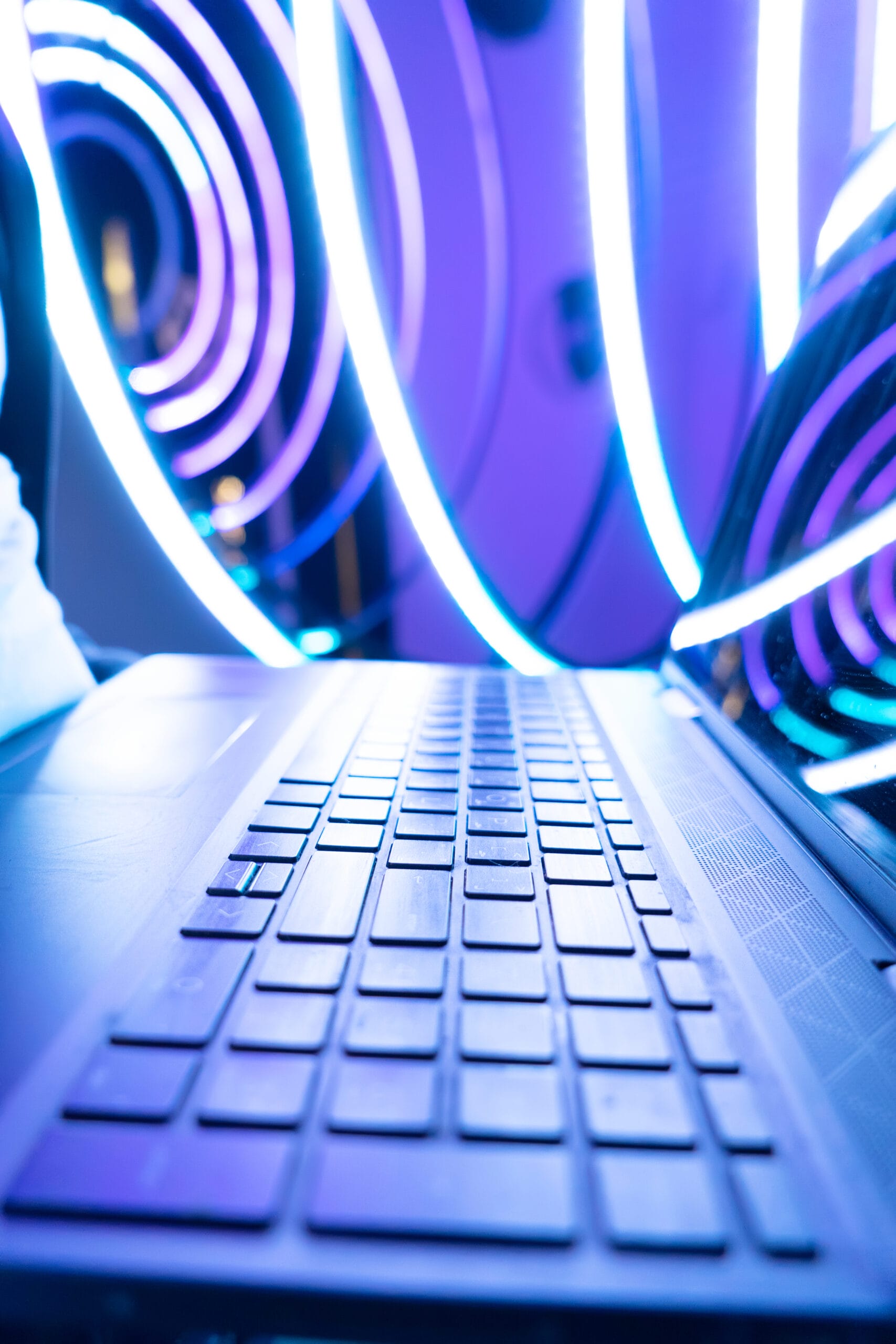 Close-up of a laptop keyboard with vibrant neon lights in the background.