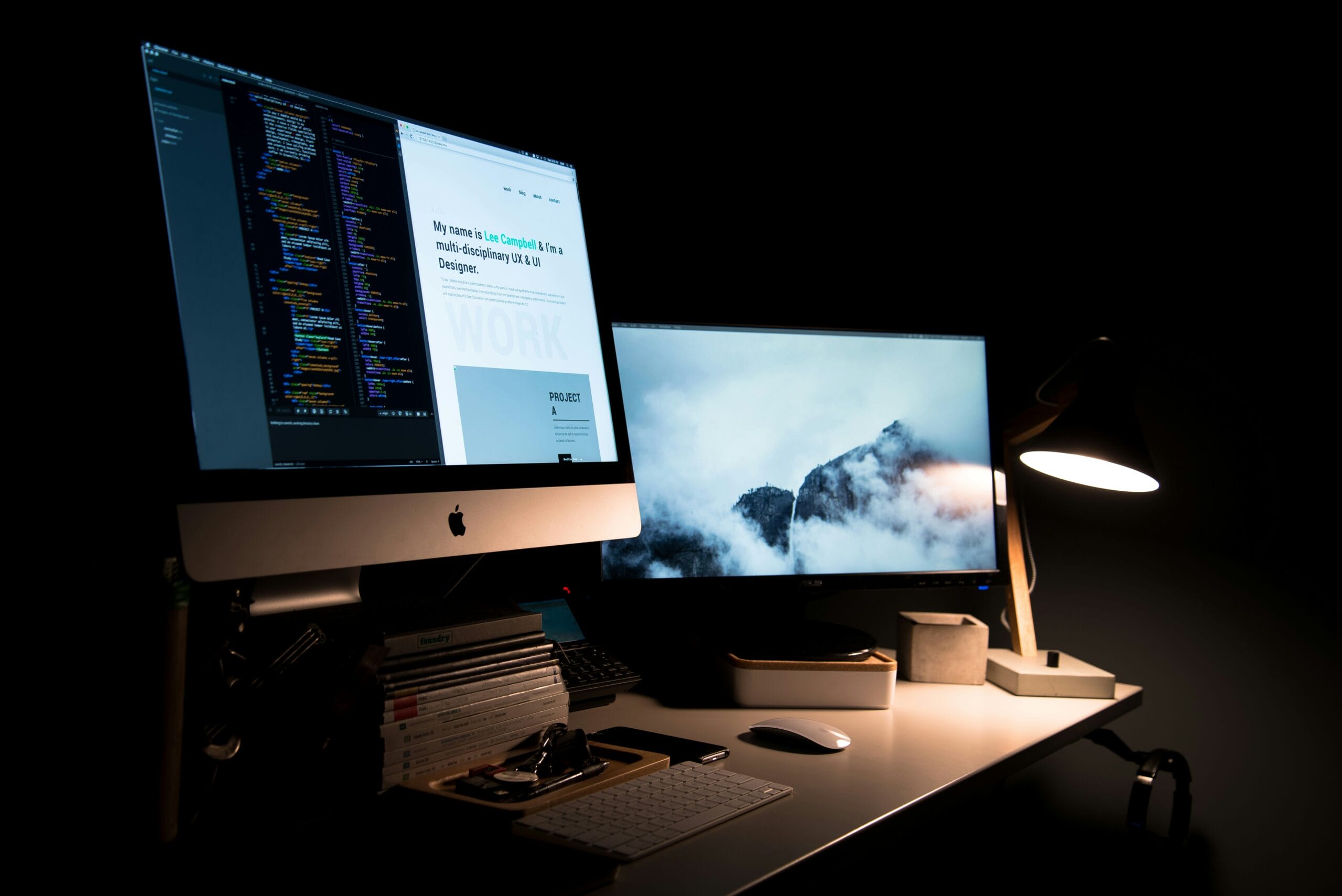 A modern workspace featuring two monitors, a desk lamp, and organized stationery.