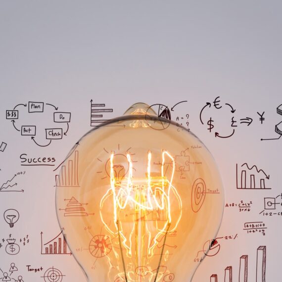 A glowing light bulb in front of various business diagrams and sketches.