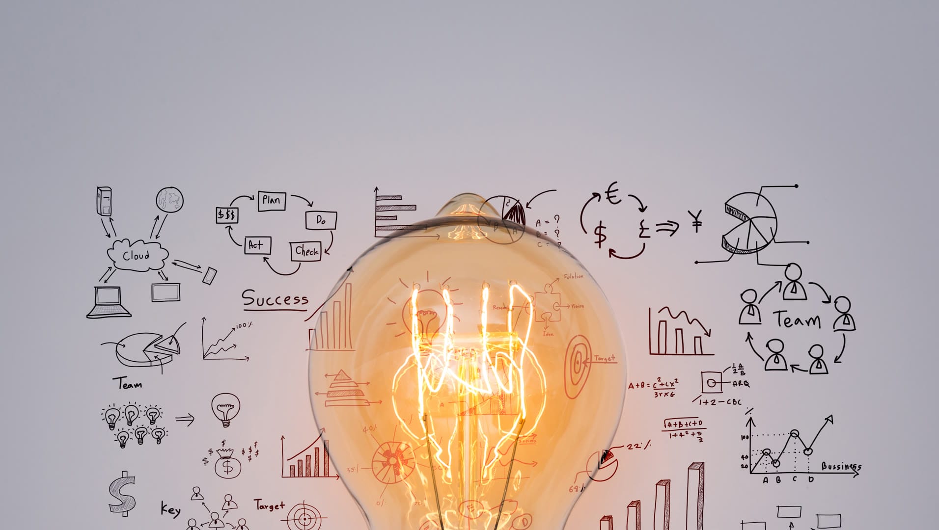 A glowing light bulb in front of various business diagrams and sketches.