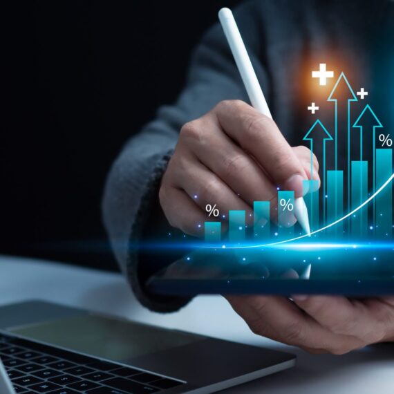 A person using a stylus on a tablet to analyze financial data with graphs.