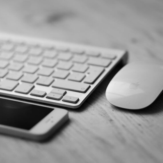 A minimalist workspace featuring a keyboard, mouse, and smartphone on a wooden surface.