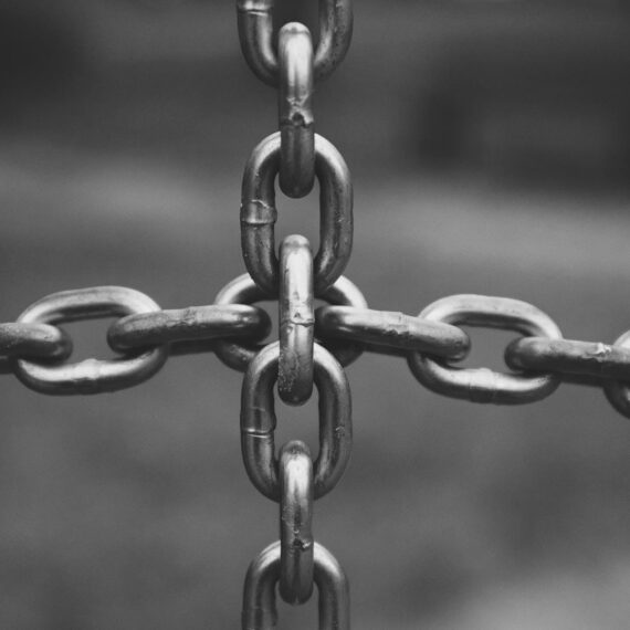 Close-up of interlocking metal chains forming a cross pattern.