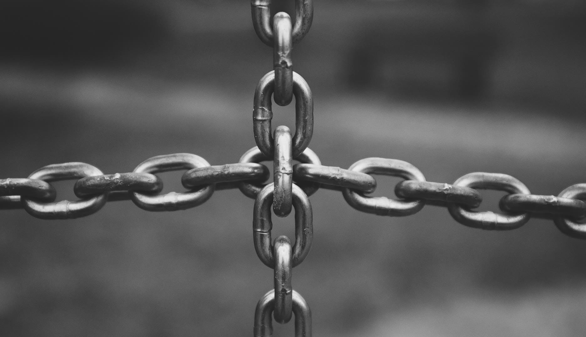 Close-up of interlocking metal chains forming a cross pattern.
