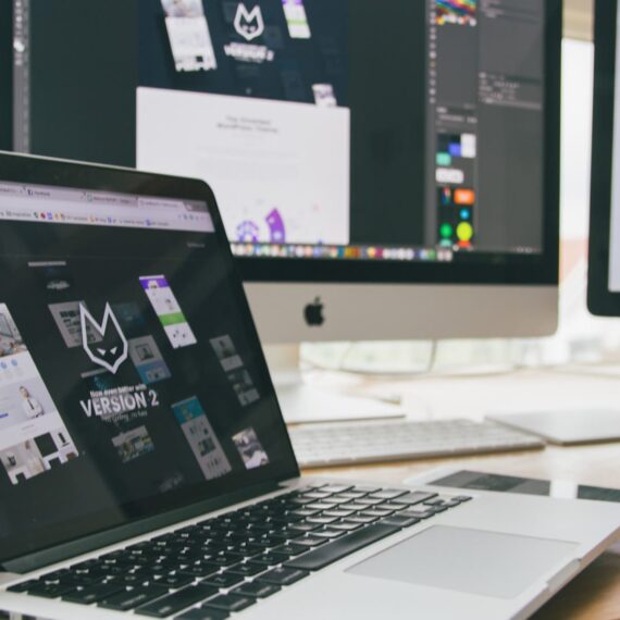 A workspace featuring a laptop and two monitors displaying web design projects.