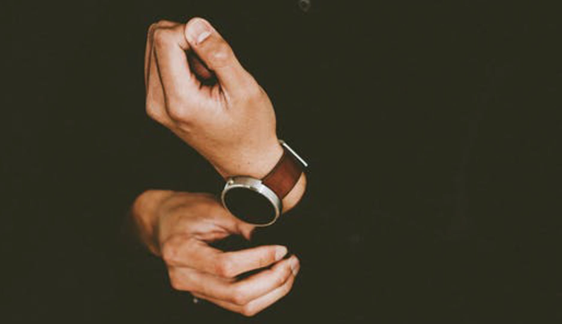 A close-up of a person adjusting a stylish watch on their wrist.