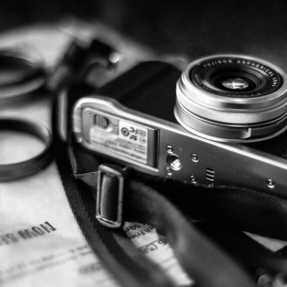 A vintage camera resting on a textured surface with lens attachments nearby.