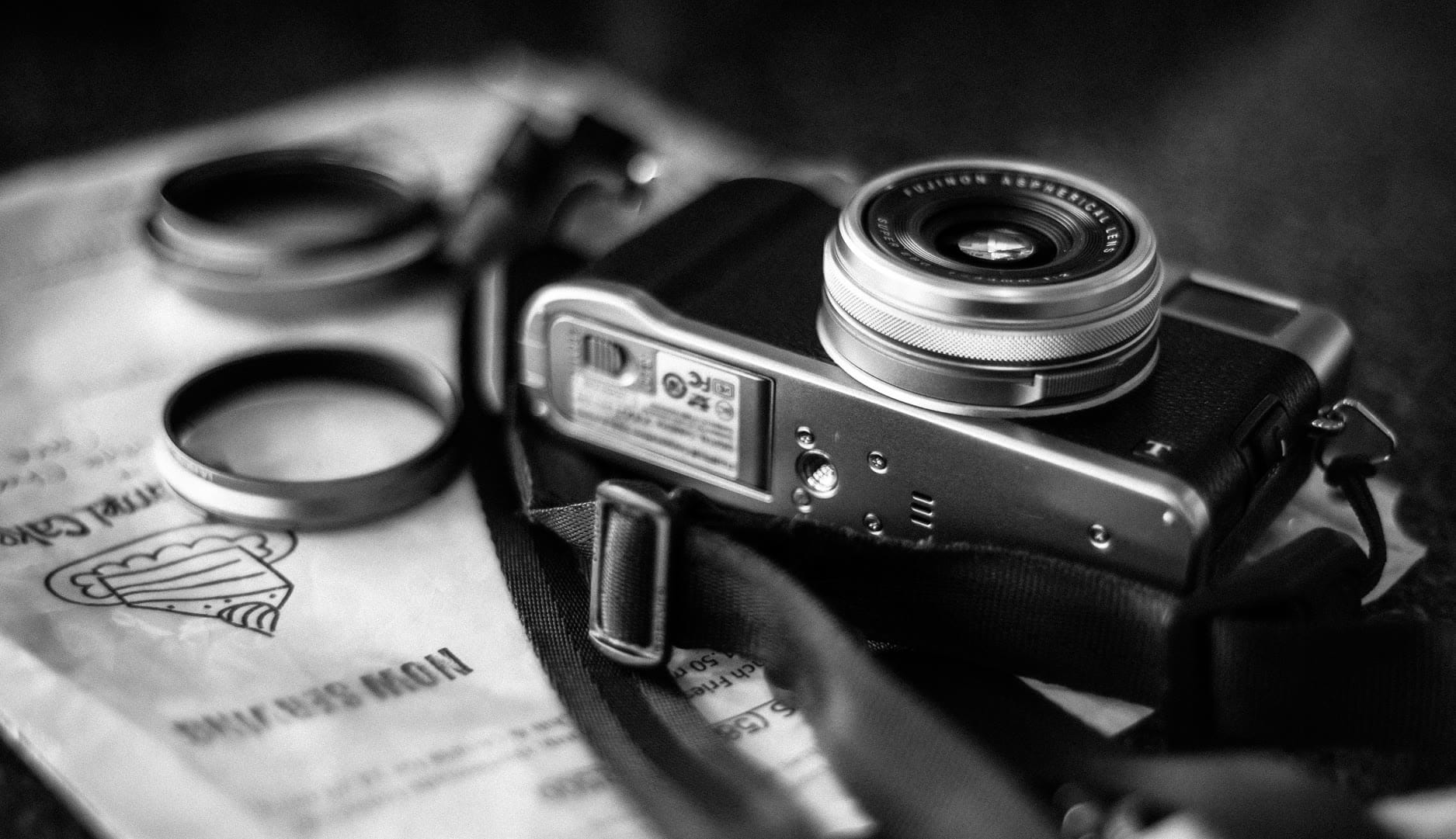 A vintage camera resting on a textured surface with lens attachments nearby.