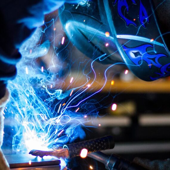 A welder working with sparks and bright blue light from welding equipment.