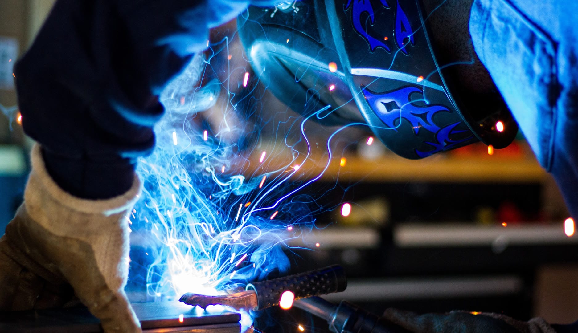 A welder working with sparks and bright blue light from welding equipment.