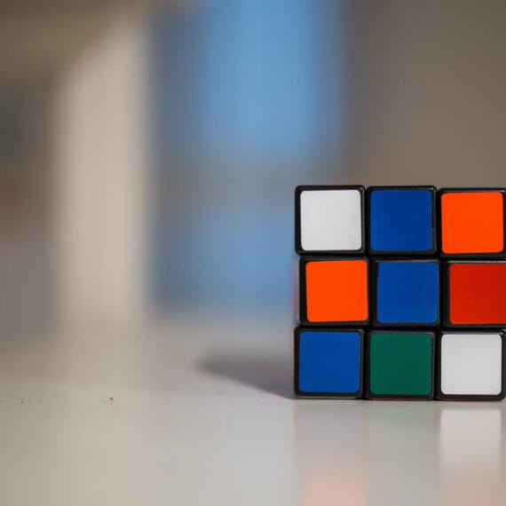 A partially solved Rubik's Cube on a white surface with a blurred background.