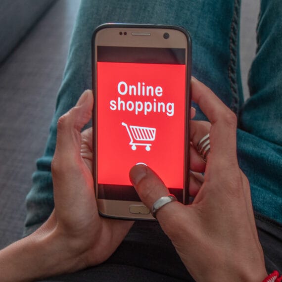 A person holding a smartphone displaying an online shopping screen.