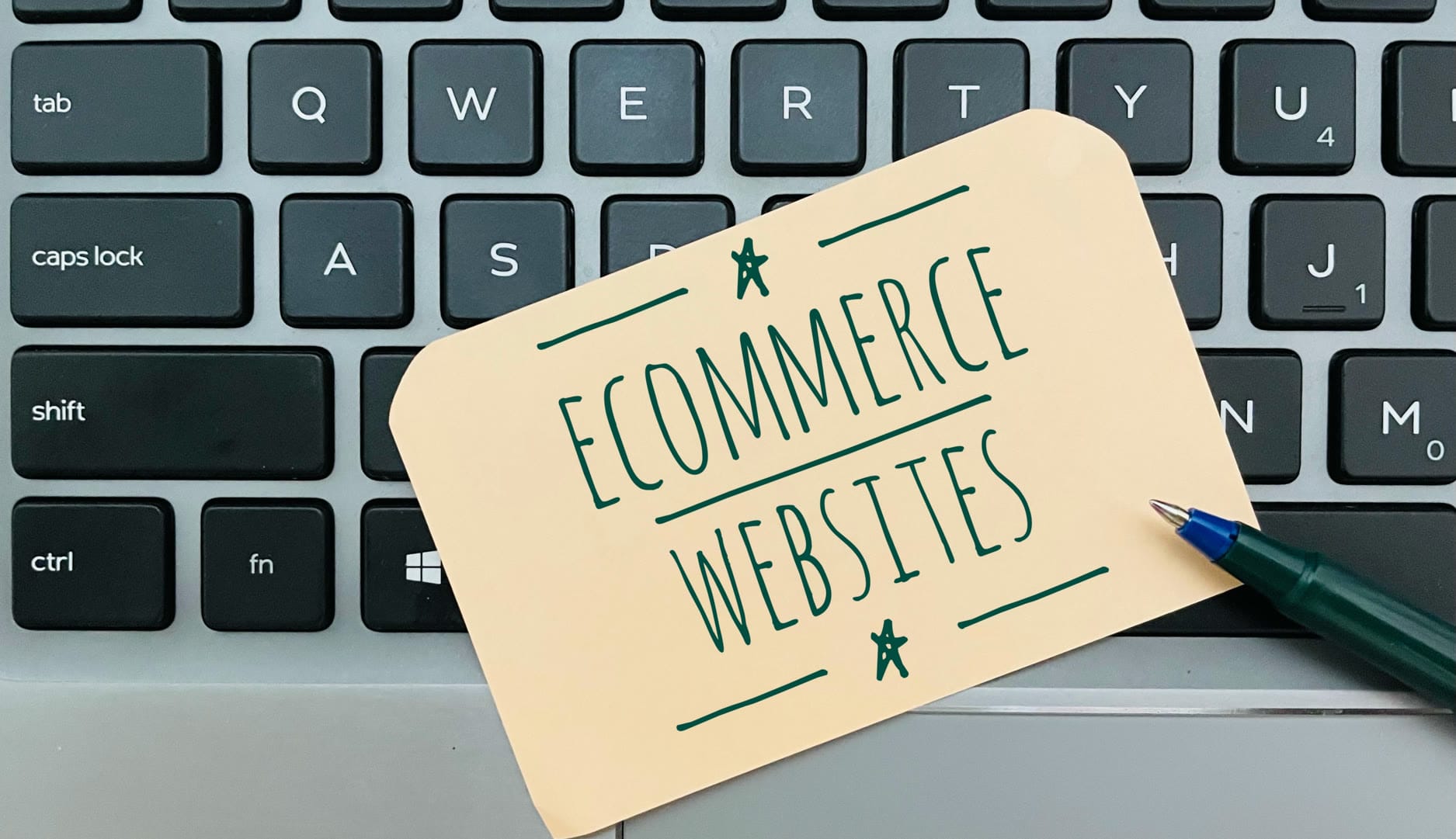 A note reading 'Ecommerce Websites' placed on a laptop keyboard.