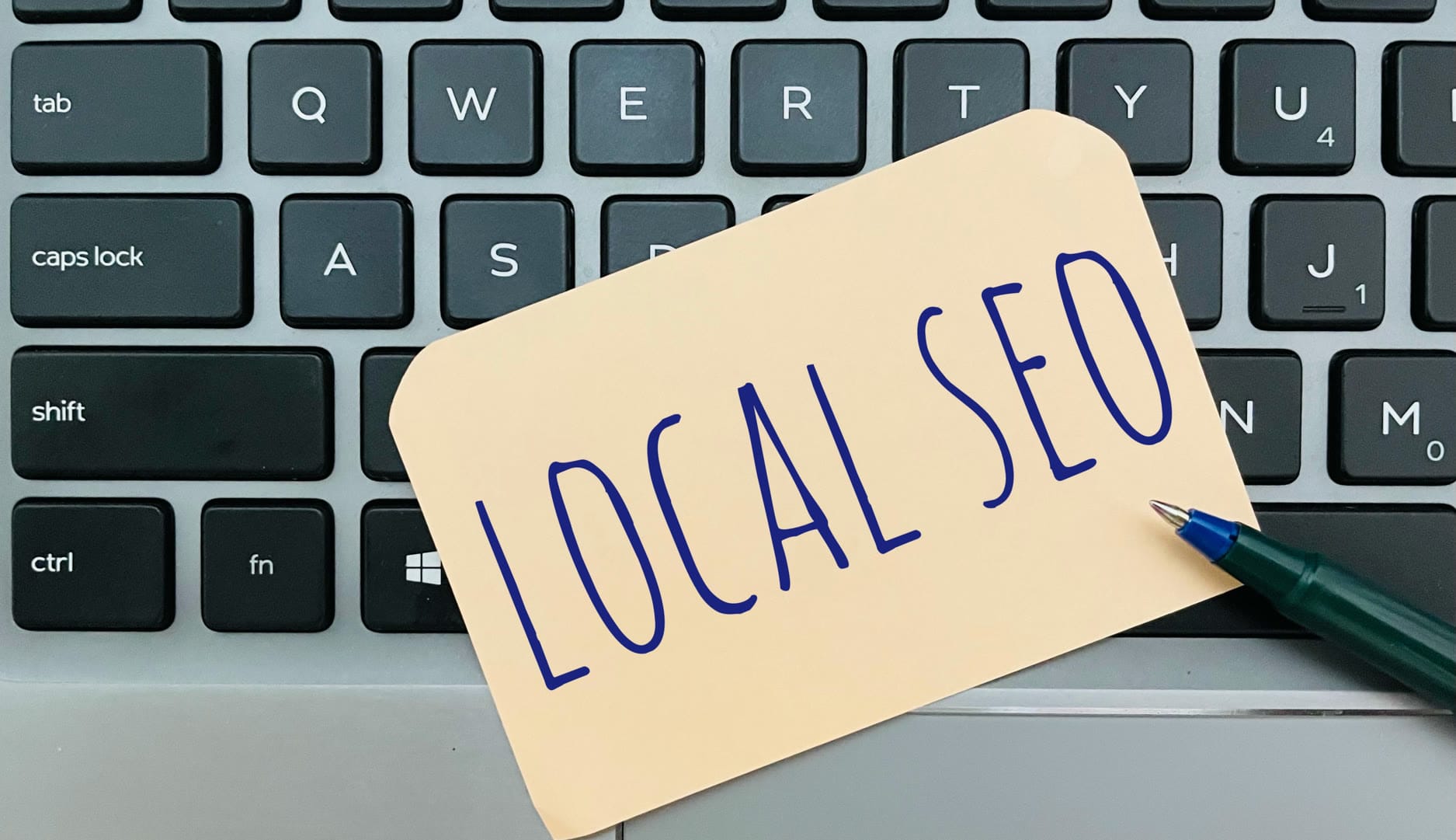 A note with 'LOCAL SEO' written on it placed on a laptop keyboard.