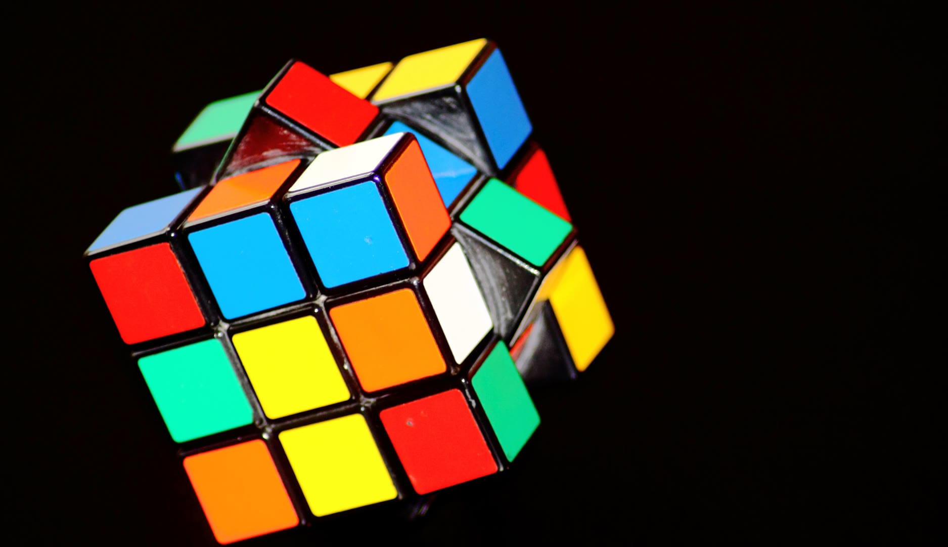 A partially solved Rubik's Cube with vibrant colors against a dark background.