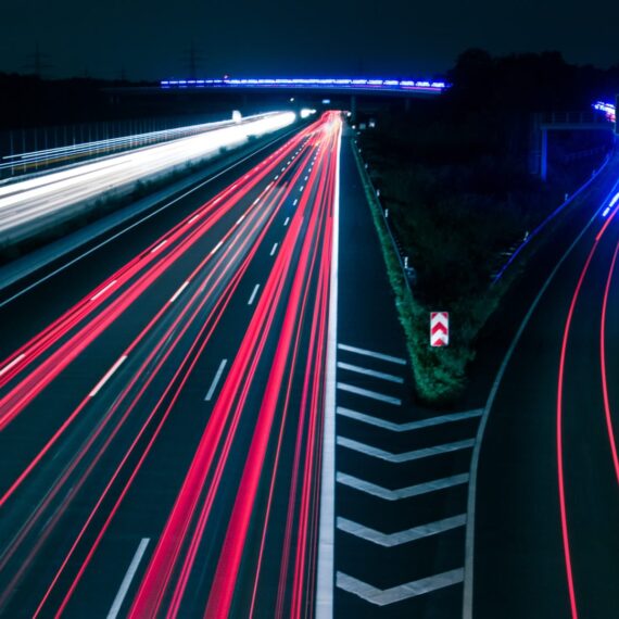 Long exposure shot of a highway at night with streaks of red and white light.