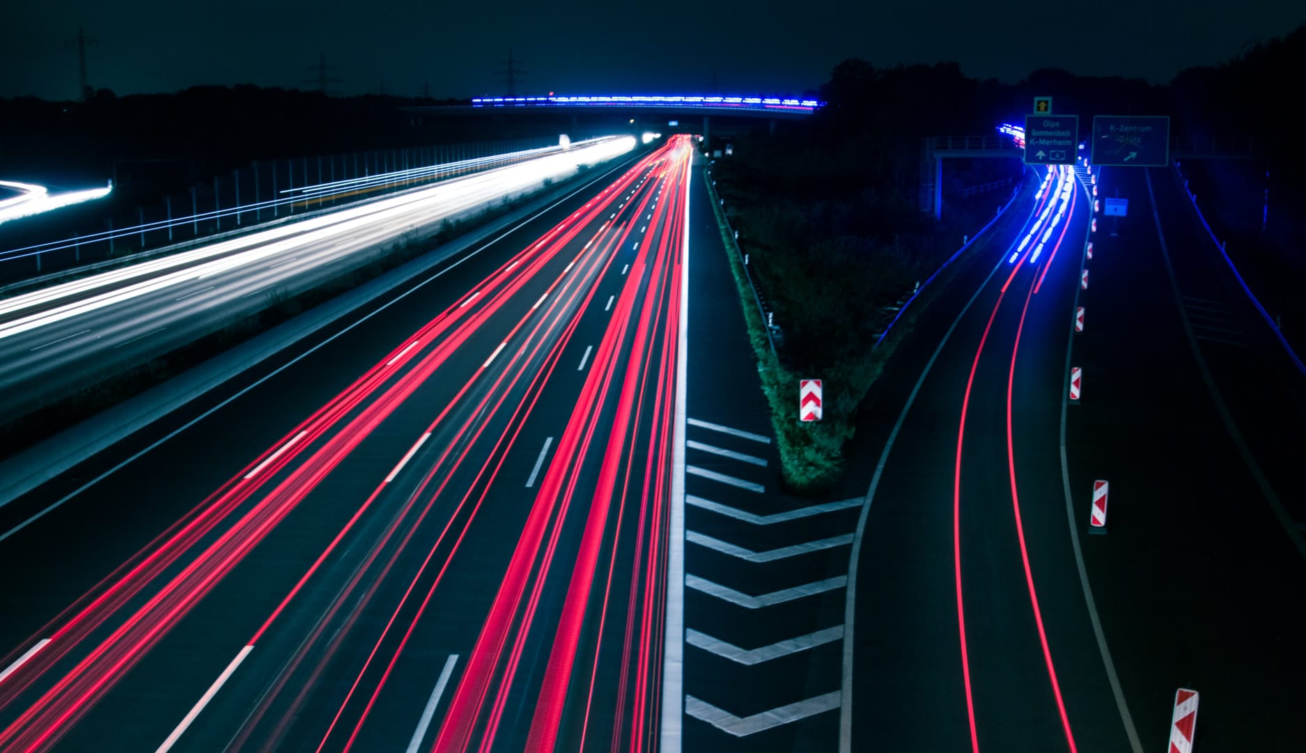 Long exposure shot of a highway at night with streaks of red and white light.