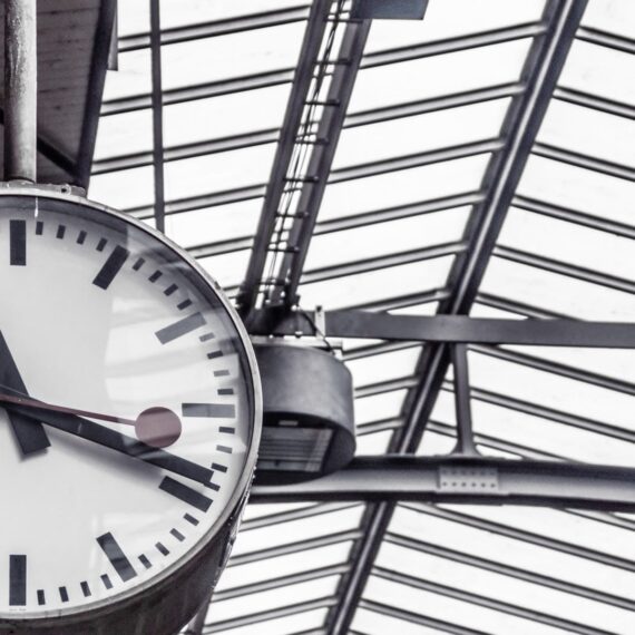 A large round clock hanging in a modern train station.
